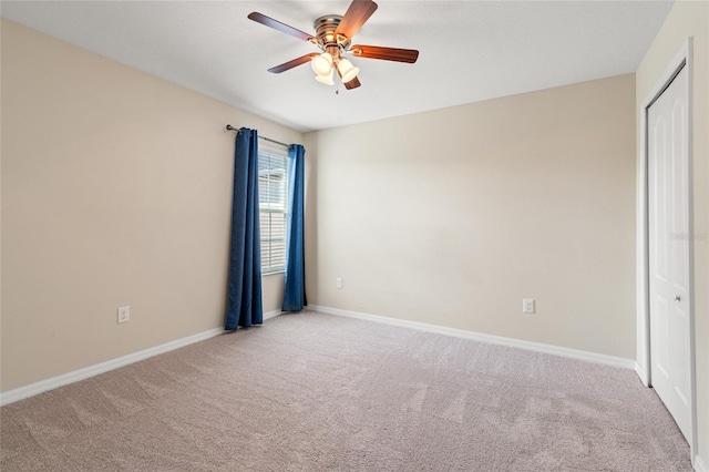 carpeted empty room with baseboards and a ceiling fan