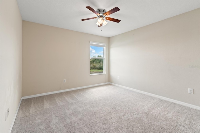 empty room with carpet, a ceiling fan, and baseboards