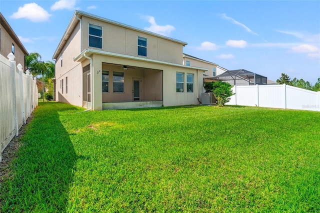 rear view of property with stucco siding, a fenced backyard, central AC unit, and a yard