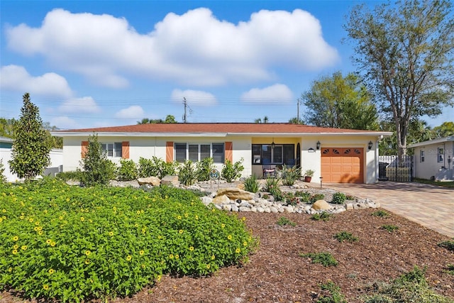 ranch-style house featuring a garage, decorative driveway, fence, and stucco siding