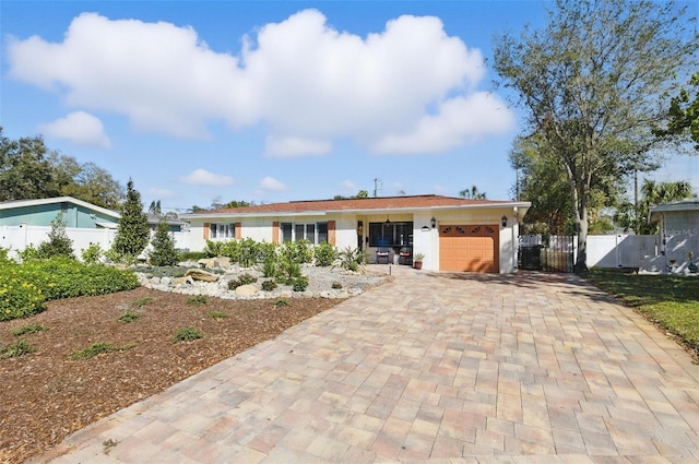 ranch-style home featuring a garage, decorative driveway, fence, and a gate