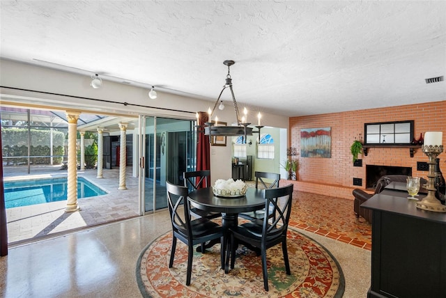 dining room with a textured ceiling, brick wall, a brick fireplace, and visible vents