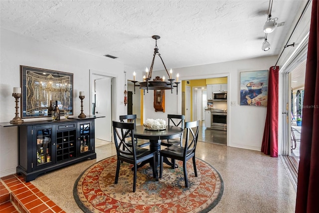 dining room with baseboards, visible vents, an inviting chandelier, a textured ceiling, and speckled floor