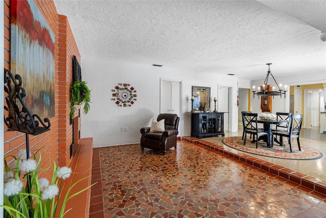 living area with visible vents, a chandelier, and a textured ceiling