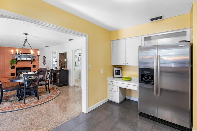 kitchen with visible vents, decorative light fixtures, light countertops, white cabinetry, and stainless steel refrigerator with ice dispenser