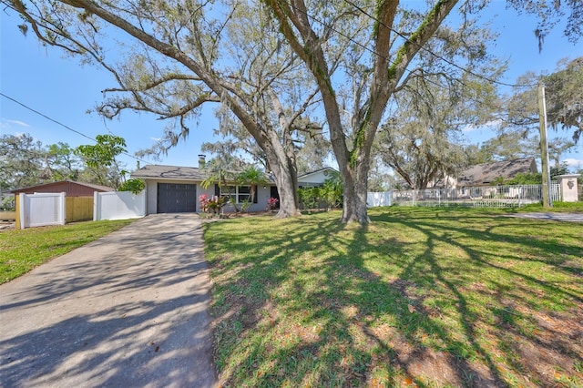 view of front facade with a garage, concrete driveway, fence, and a front lawn