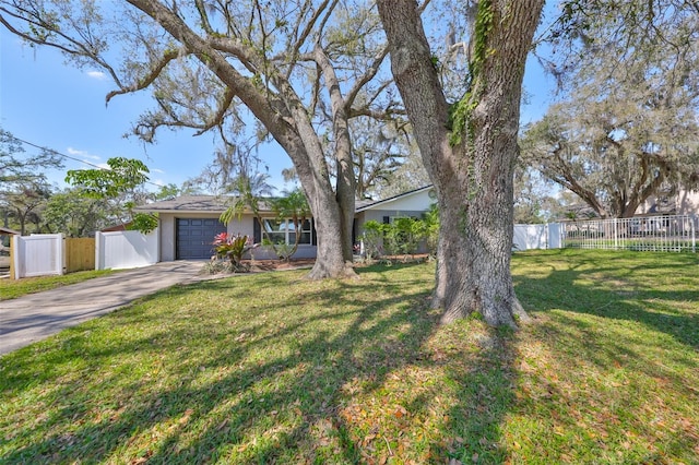 view of front facade with a garage, fence, concrete driveway, and a front yard