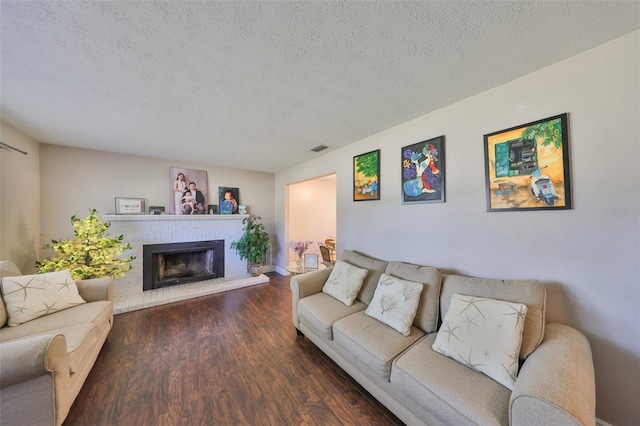 living area with a textured ceiling, a fireplace, visible vents, and wood finished floors