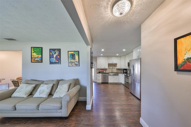 living room featuring visible vents, dark wood finished floors, a textured ceiling, and baseboards