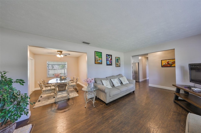 living area featuring baseboards, a textured ceiling, visible vents, and wood finished floors