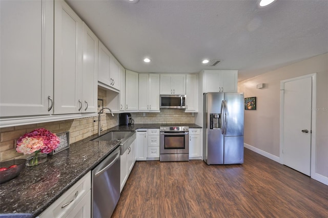 kitchen with dark wood-style floors, stainless steel appliances, backsplash, white cabinets, and a sink