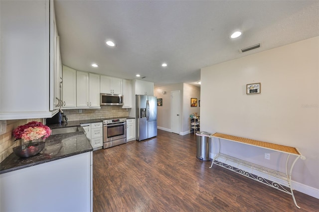 kitchen featuring tasteful backsplash, visible vents, white cabinets, dark wood-type flooring, and stainless steel appliances