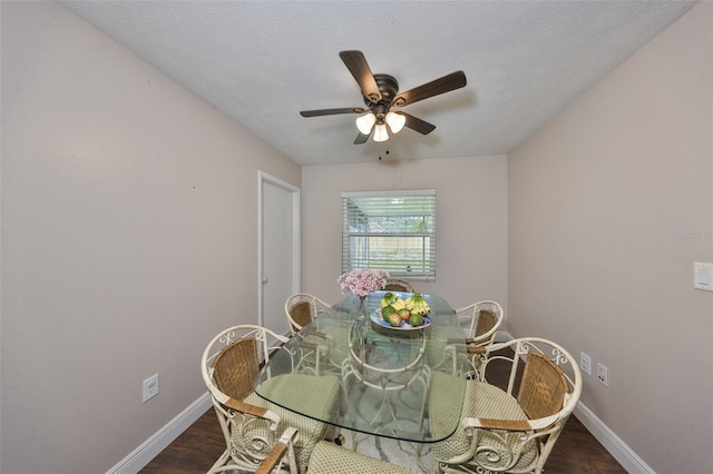 dining space with a textured ceiling, baseboards, and wood finished floors