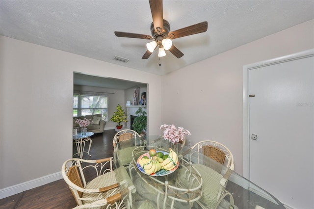 dining space with baseboards, visible vents, a ceiling fan, wood finished floors, and a textured ceiling