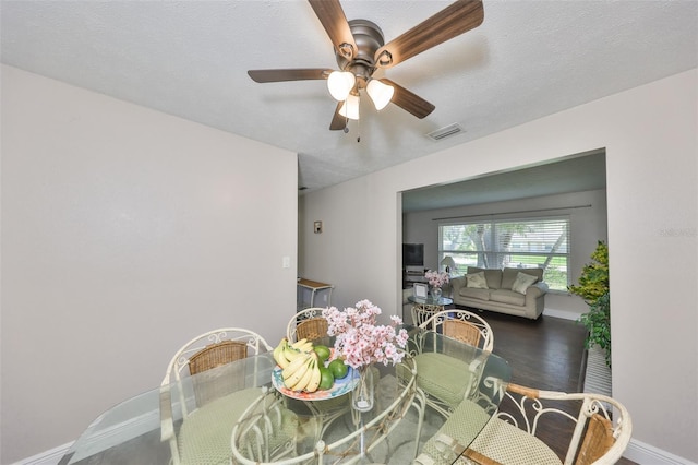 dining room featuring visible vents, a ceiling fan, a textured ceiling, wood finished floors, and baseboards