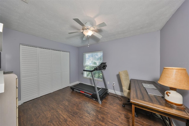 workout area with ceiling fan, a textured ceiling, baseboards, and wood finished floors