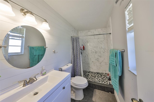 bathroom with toilet, wooden walls, vanity, tile patterned floors, and a stall shower