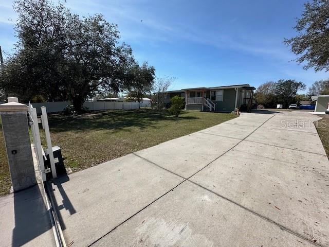 view of front of house featuring concrete driveway, a front yard, and fence