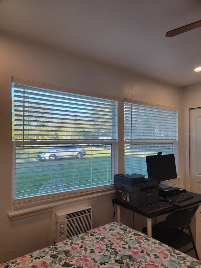 bedroom featuring ceiling fan, multiple windows, and a wall mounted AC