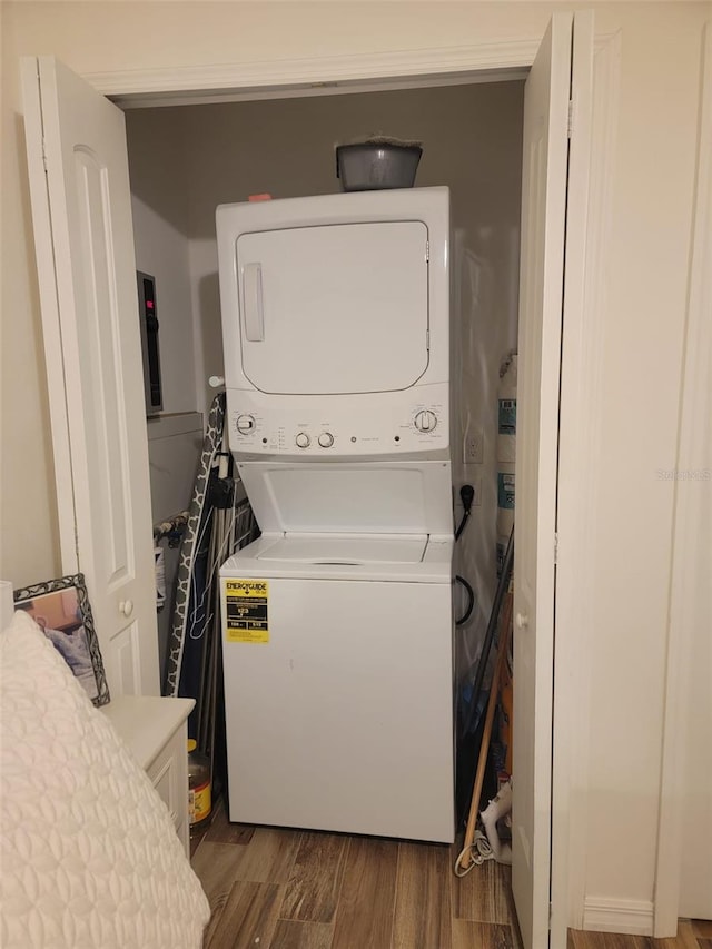 laundry room with laundry area, dark wood-type flooring, and stacked washer / drying machine