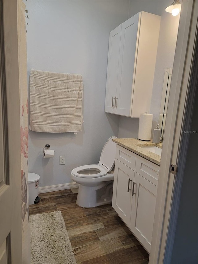 bathroom featuring baseboards, vanity, toilet, and wood finished floors