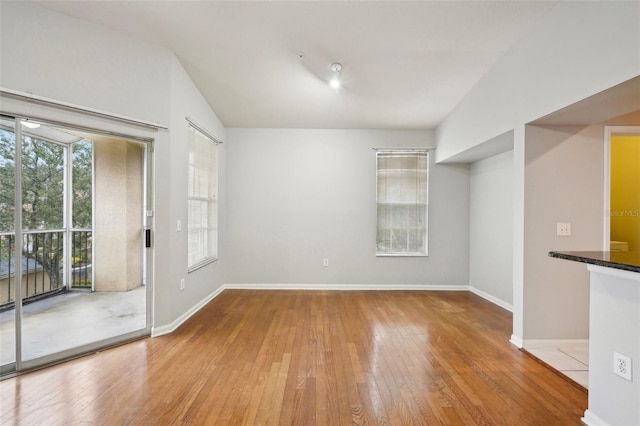 interior space featuring lofted ceiling, hardwood / wood-style floors, and baseboards