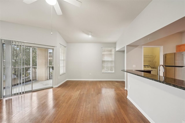 interior space featuring lofted ceiling, ceiling fan, a sink, baseboards, and hardwood / wood-style floors