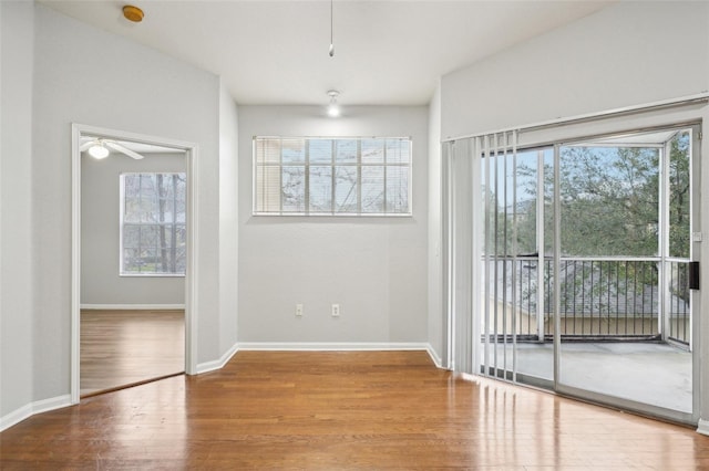 spare room featuring baseboards, ceiling fan, wood finished floors, and a healthy amount of sunlight