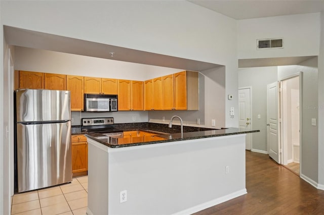 kitchen with visible vents, appliances with stainless steel finishes, dark stone countertops, a peninsula, and baseboards