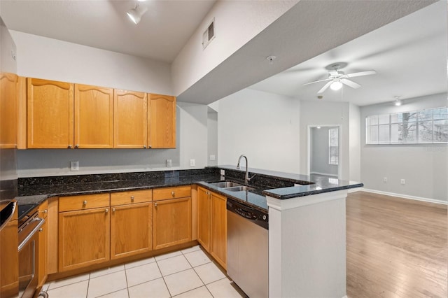 kitchen with visible vents, dark stone counters, dishwasher, a peninsula, and a sink