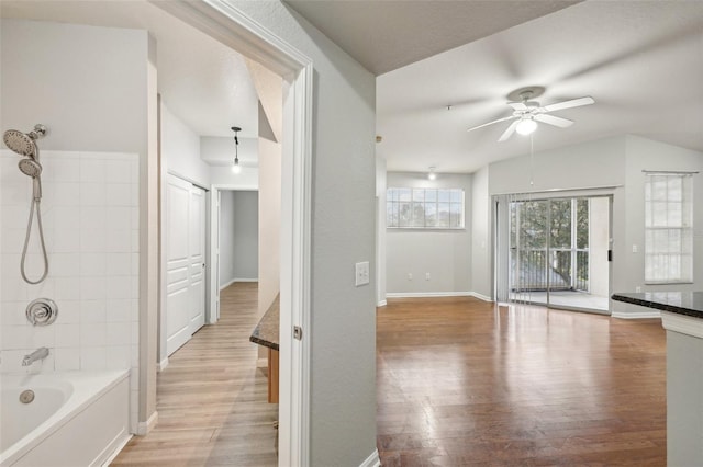 full bath featuring ceiling fan, bathtub / shower combination, baseboards, and wood finished floors