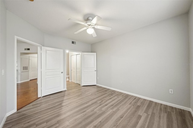 unfurnished bedroom featuring baseboards, visible vents, and light wood finished floors