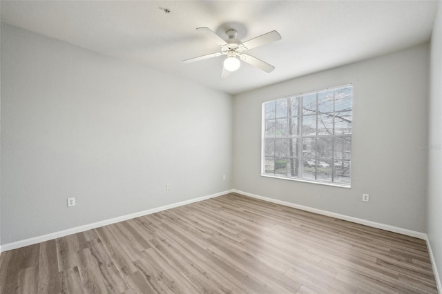 spare room featuring ceiling fan, baseboards, and wood finished floors