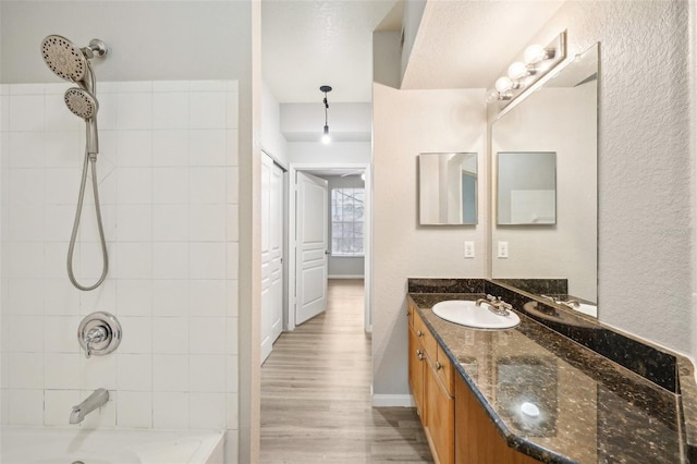 bathroom featuring vanity, baseboards, wood finished floors, and shower / bathtub combination