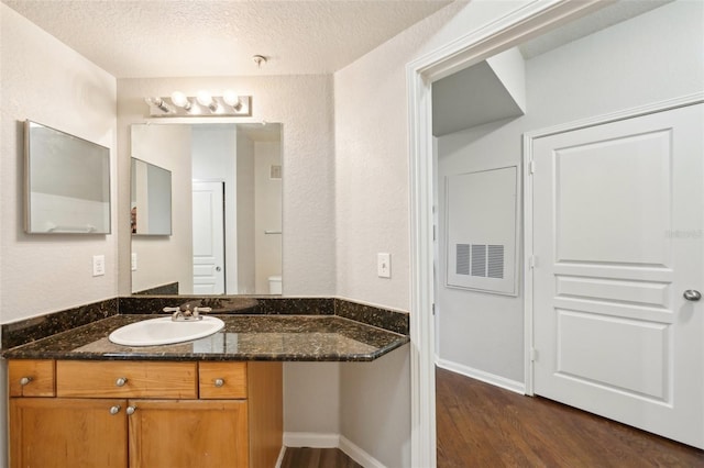 bathroom with baseboards, a textured ceiling, vanity, and wood finished floors