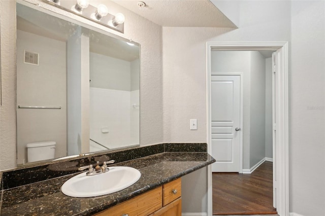 bathroom featuring toilet, visible vents, wood finished floors, and vanity