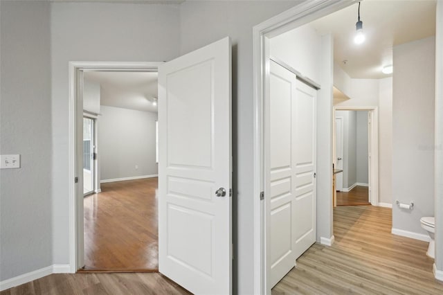 hall with baseboards and light wood finished floors