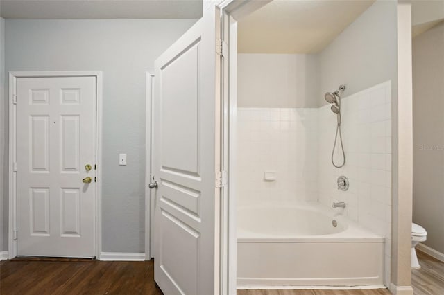 bathroom with shower / washtub combination, wood finished floors, toilet, and baseboards