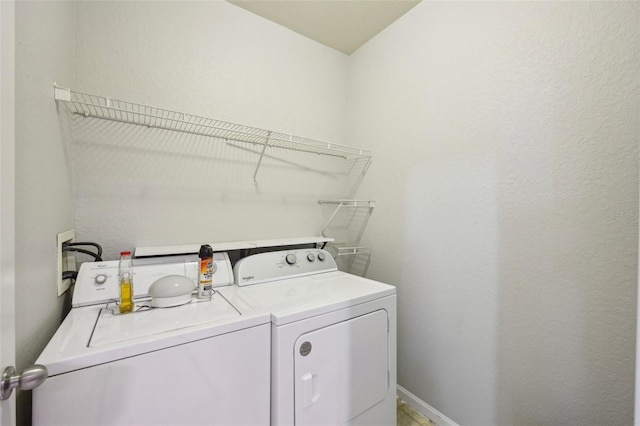 clothes washing area featuring laundry area, baseboards, and washer and dryer