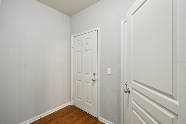 doorway to outside featuring baseboards and dark wood finished floors