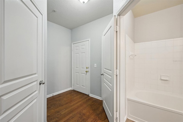 full bathroom featuring  shower combination, a textured ceiling, baseboards, and wood finished floors