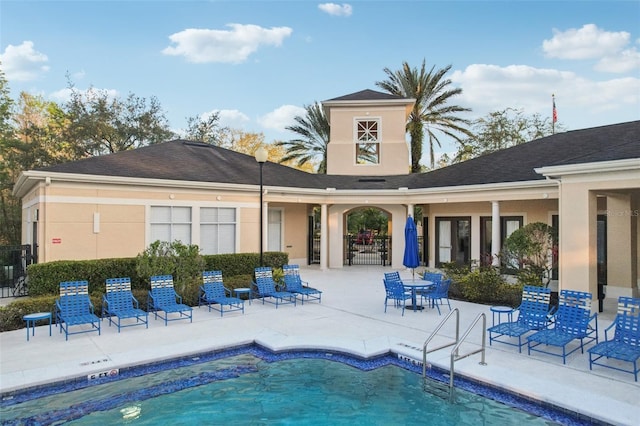 rear view of house with a patio, a community pool, and stucco siding