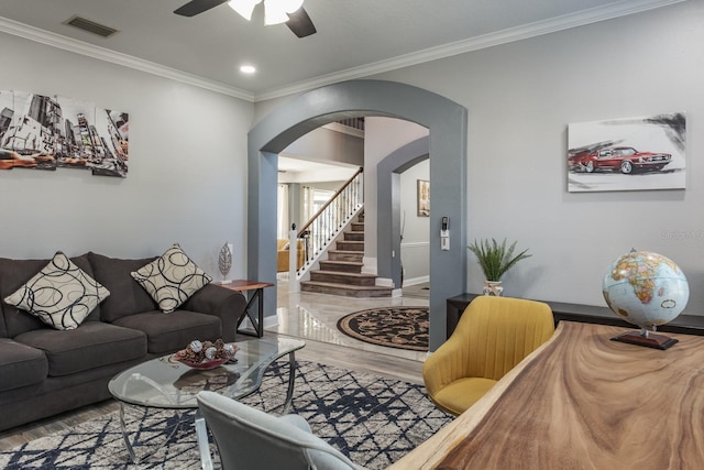 living area featuring visible vents, arched walkways, wood finished floors, stairs, and crown molding