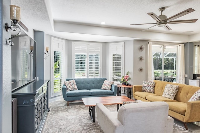 living room featuring ceiling fan, a textured ceiling, and plenty of natural light