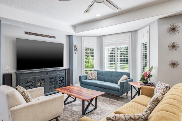 living area with ceiling fan, a textured ceiling, and wood finished floors