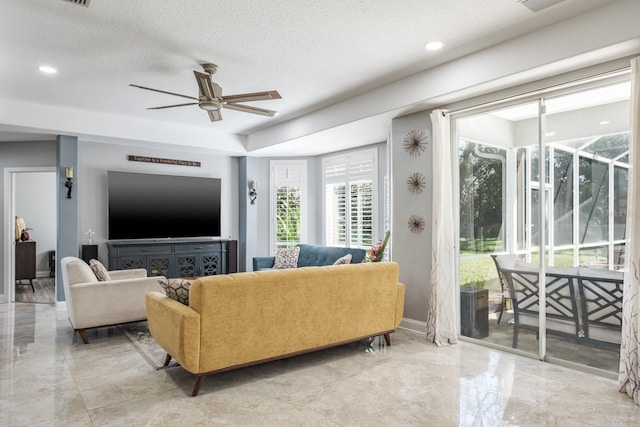 living room featuring marble finish floor, ceiling fan, baseboards, and a textured ceiling