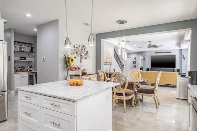 kitchen with wine cooler, decorative light fixtures, open floor plan, white cabinets, and a kitchen island