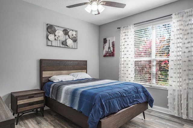 bedroom with ceiling fan, a textured ceiling, wood finished floors, and baseboards