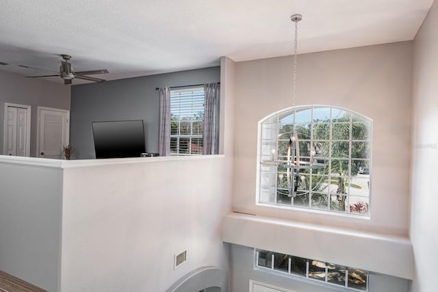 interior space with a textured ceiling, visible vents, and a ceiling fan