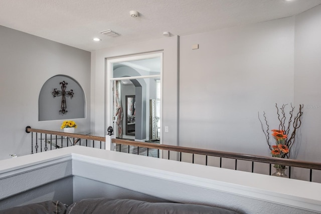 hallway featuring a textured ceiling, visible vents, and recessed lighting